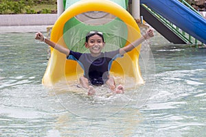 Asian little boy playing water slide at water park having fun on vacation.
