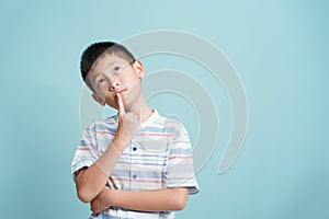 Asian little boy standing thinking on blue background isolated, Asia man look up and copy space