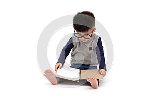 Asian little boy wearing glasses and reading a book isolated over white background