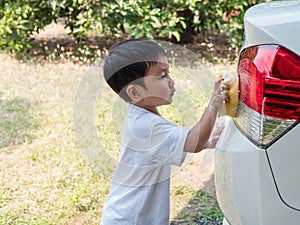 Asian little child boy 3 years old washing white car.