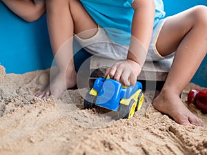 Asian little child boy hand playing car toy and sand in sandbox