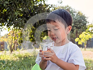 Asian little child boy holding glass of orange juice with smiling happy face