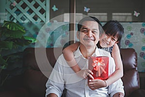 Asian little child daughters congratulating dad and giving him postcard and gift box with smiling and hugging.Concept of Happy