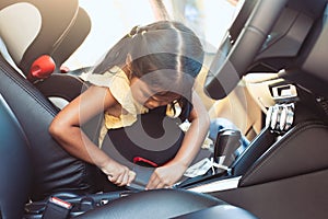 Asian little child girl is fastening security belt by herself