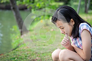 Asian little child girl feeling stressed,female worried bites finger nails in outdoor park,girl patient with nervous expression,