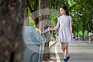 Asian little child girl hand holding plastic bottle,putting plastic water bottle in recycling bin,tourist woman hand throwing