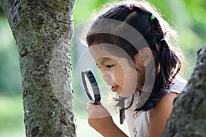 Asian little child girl looking through a magnifying glass