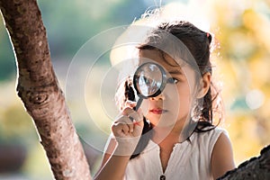 Asian little child girl looking through a magnifying glass