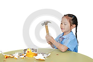 Asian little child girl in school uniform breaking piggy bank isolated on white background at table. Schoolgirl with Money saving