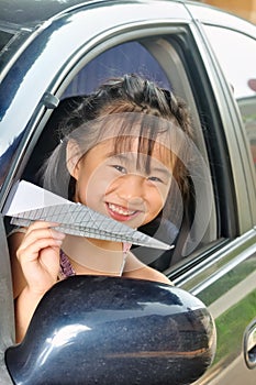 Asian little child holding paper plane in the car