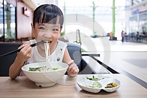Asian little Chinese girl eating beef noodles soup
