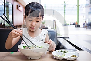 Asian little Chinese girl eating beef noodles soup