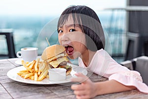 Asian Little Chinese Girl eating hamburger