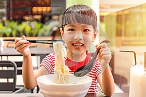 Asian little Chinese girl eating noodles soup