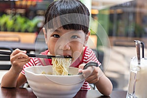 Asian little Chinese girl eating noodles soup