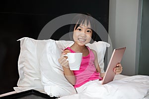 Asian Little Chinese Girl playing tablet in bed