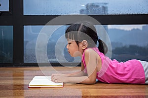 Asian little Chinese girl reading a book near the window