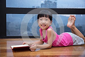Asian little Chinese girl reading a book near the window