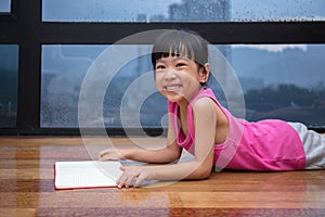 Asian little Chinese girl reading a book near the window