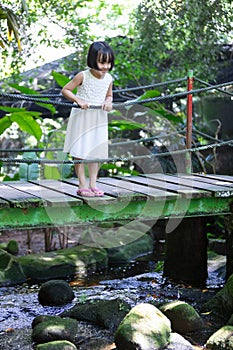 Asian Little Chinese Girl standing on the wooden bridge