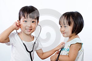 Asian Little Chinese Girls Playing as Doctor and Patient with St photo
