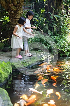 Asian Little Chinese Sisters feeding fish