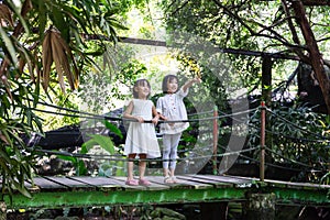 Asian Little Chinese Sisters standing on the wooden bridge