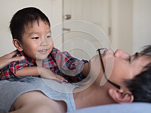 Asian little cute child boy playing with father in bedroom with happy smiling face.