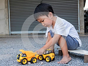Asian little cute child boy playing yellow car truck toy outdoor