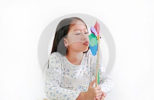 Asian little girl child blowing colorful pinwheel over white background. Kid hold and playing windmill in hand