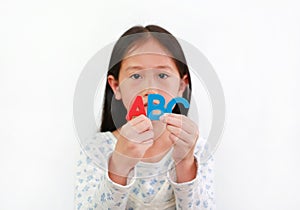 Asian little girl child holding ABC sponge text in hands over white background. Education and development concept. Focus at