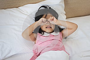 Asian little girl crying on bed