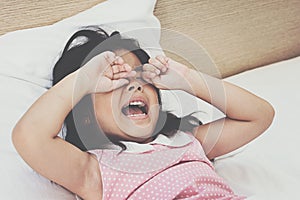Asian little girl crying on bed.