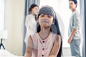 Asian little girl crying while parents fighting or quarrel conflict. Young kid daughter sit on bed feel heart broken with tears