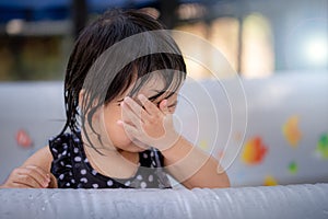 Asian little girl is crying. She wipes her tears. Stay in a rubberized swimming pool. Baby age 2-3 years old.