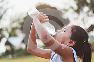 asian little girl drinking fresh water from plastic bottle with