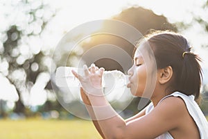asian little girl drinking fresh water from plastic bottle with