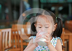 Asian little girl is drinking a milk from glass