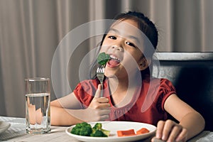 Asian little girl eating healthy vegetables with relish