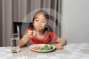 Asian little girl eating healthy vegetables with relish