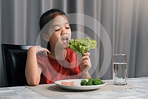 Asian little girl eating healthy vegetables with relish