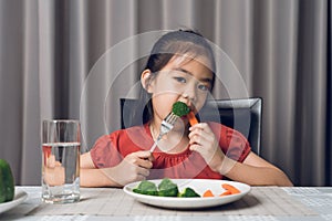 Asian little girl eating healthy vegetables with relish