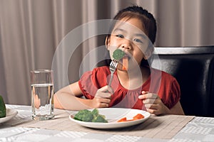 Asian little girl eating healthy vegetables with relish