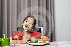 Asian little girl eating healthy vegetables with relish