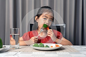 Asian little girl eating healthy vegetables with relish