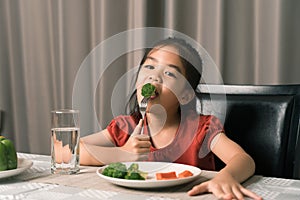 Asian little girl eating healthy vegetables with relish