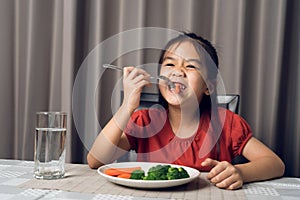 Asian little girl eating healthy vegetables with relish