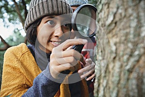 Asian little girl examining the tree stem through with magnifying glass While his mother stood behind in the morning photo