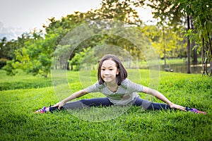 Asian little girl exercising at the outdoor park on the lawn is a meditation practice,child exercise in nature in the morning,