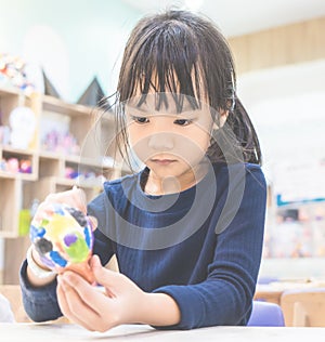 Asian little girl is focusing on painting art doll